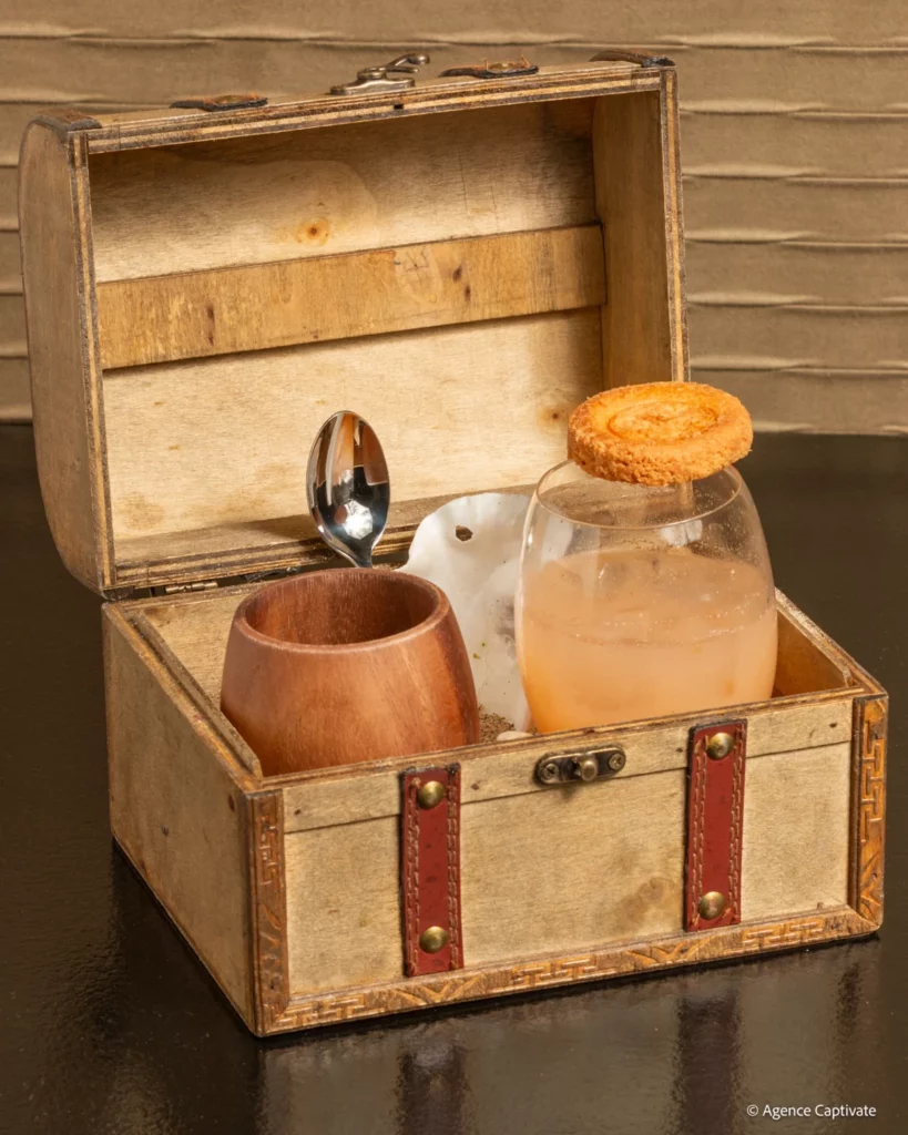 Cocktail présenté dans un coffre en bois avec une cuillère et un biscuit