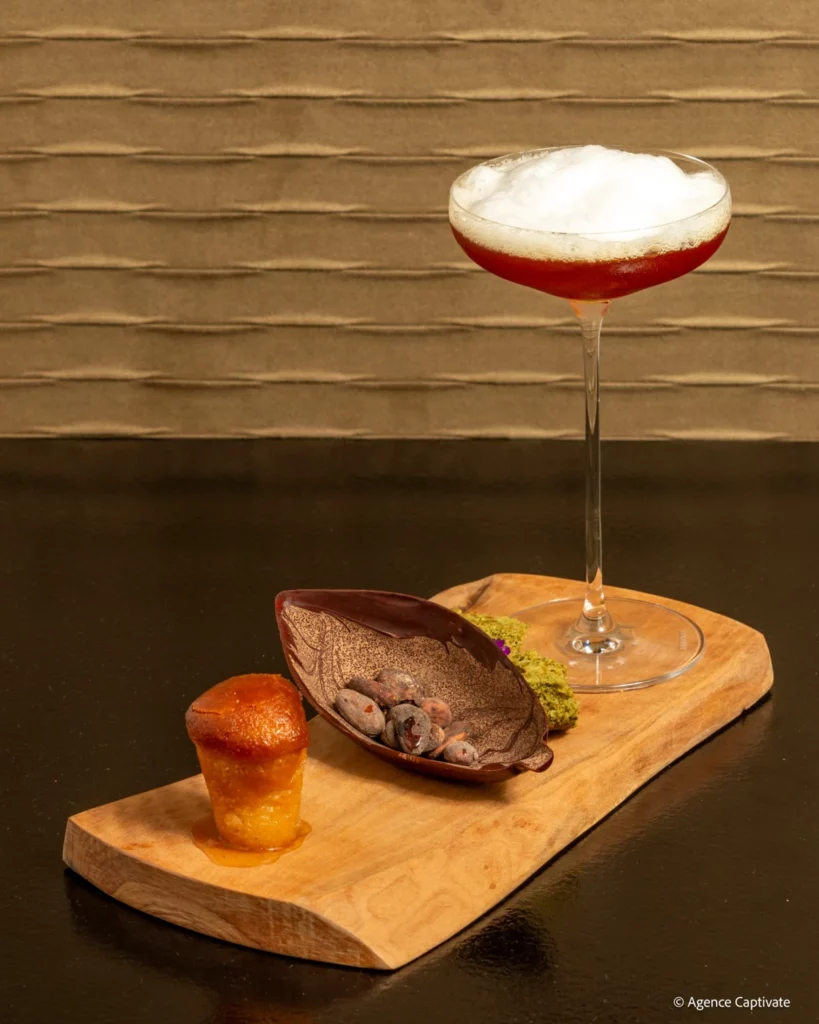 Cocktail en coupe sur une planche avec une cabosse et une bouchée
