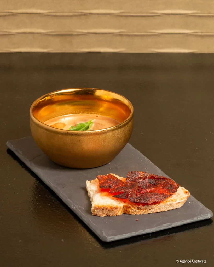 Cocktail dans un bol doré, servi sur ardoise avec une tartine